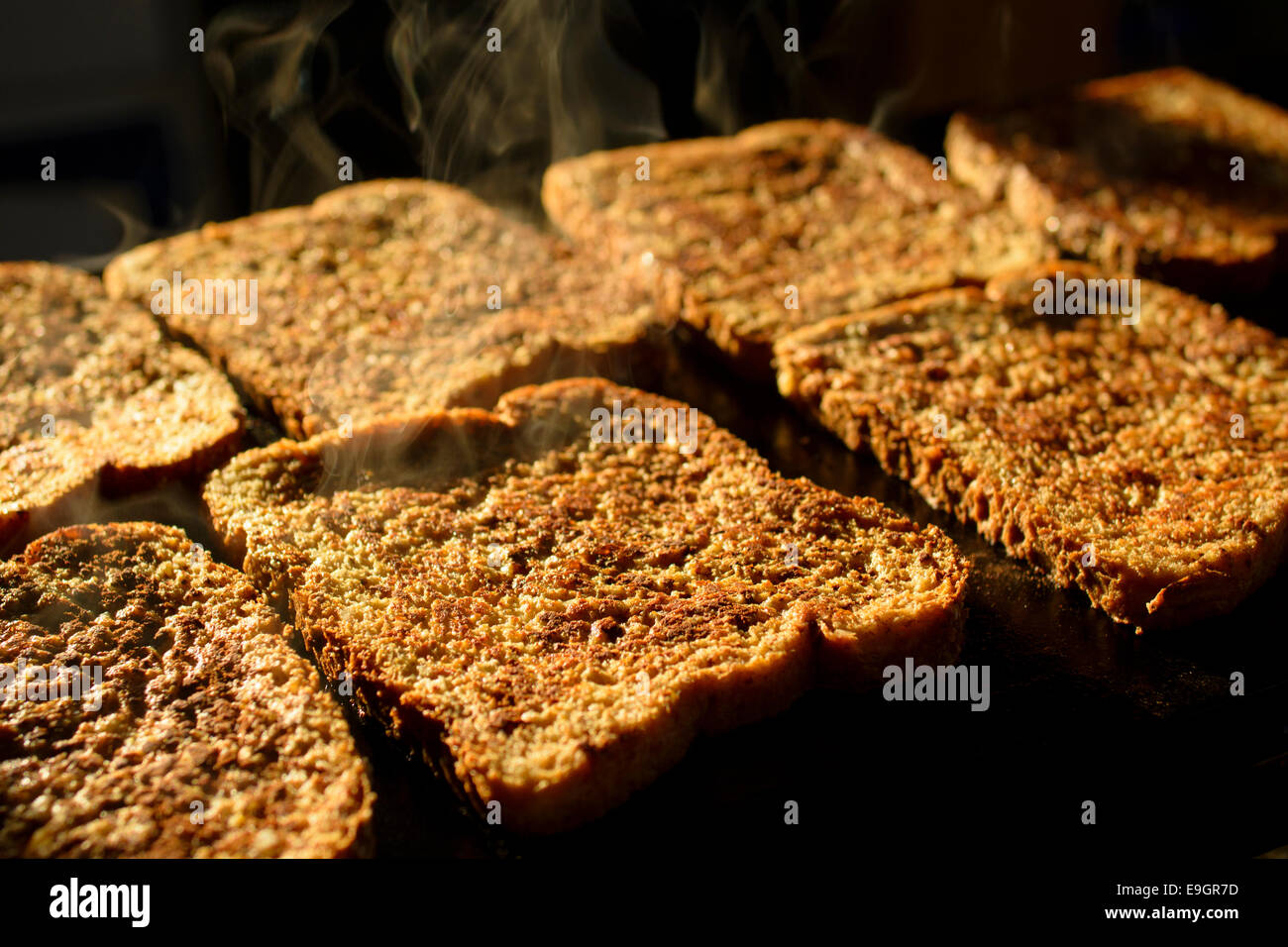Steamy hot French toast with cinnamon being fried on a griddle pan