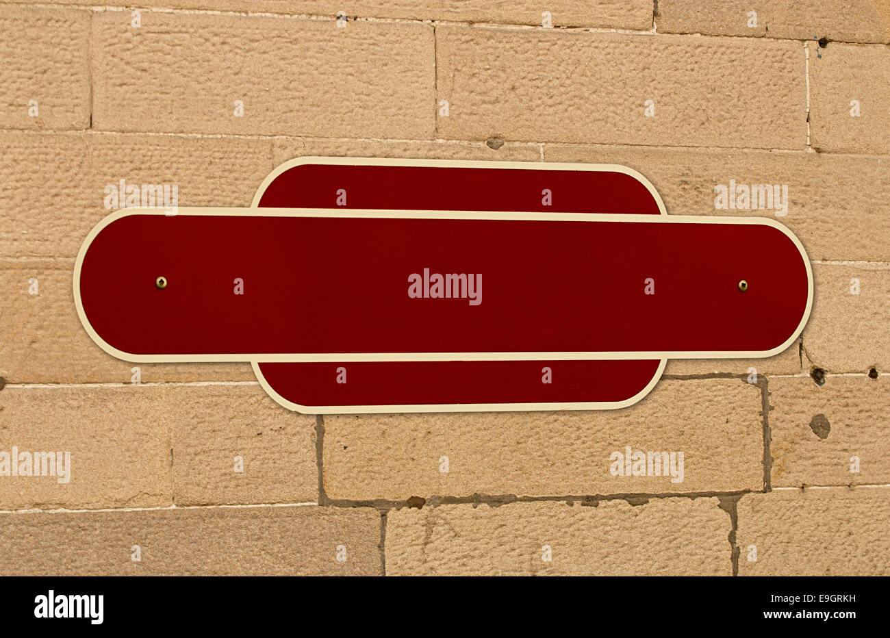 Traditional blank railway sign on the wall of a train station for insertion of your message or place name in middle. Stock Photo