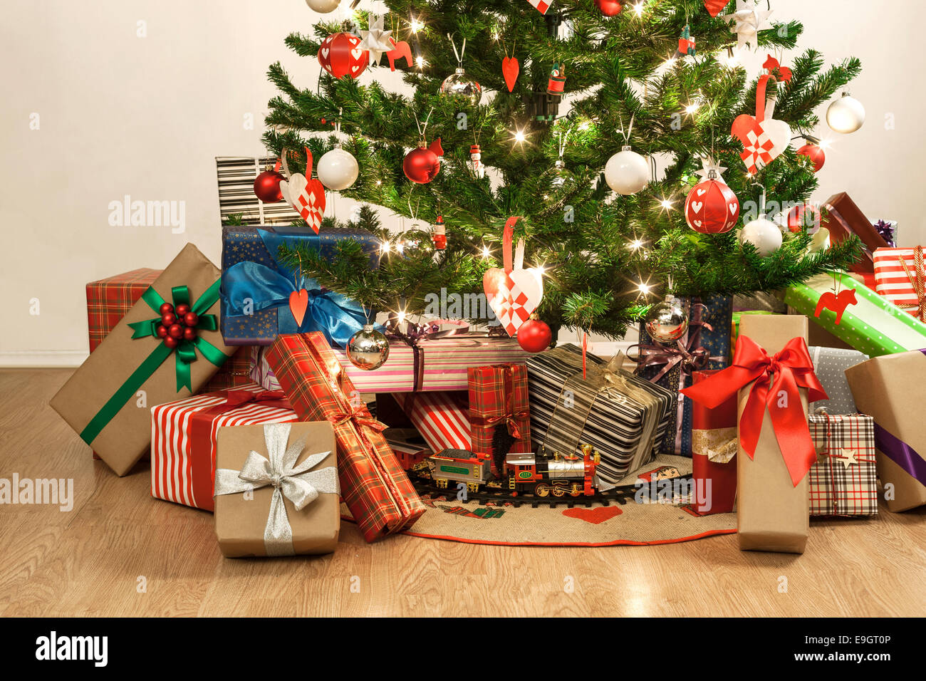 beautifully decorated christmas tree with a toy train and lots of presents Stock Photo