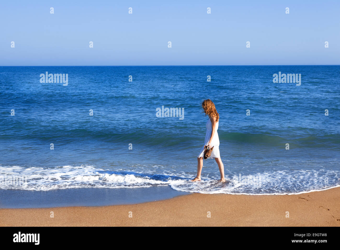 Holidaymaker goes on the beach of Spain walk with feet in water Stock Photo