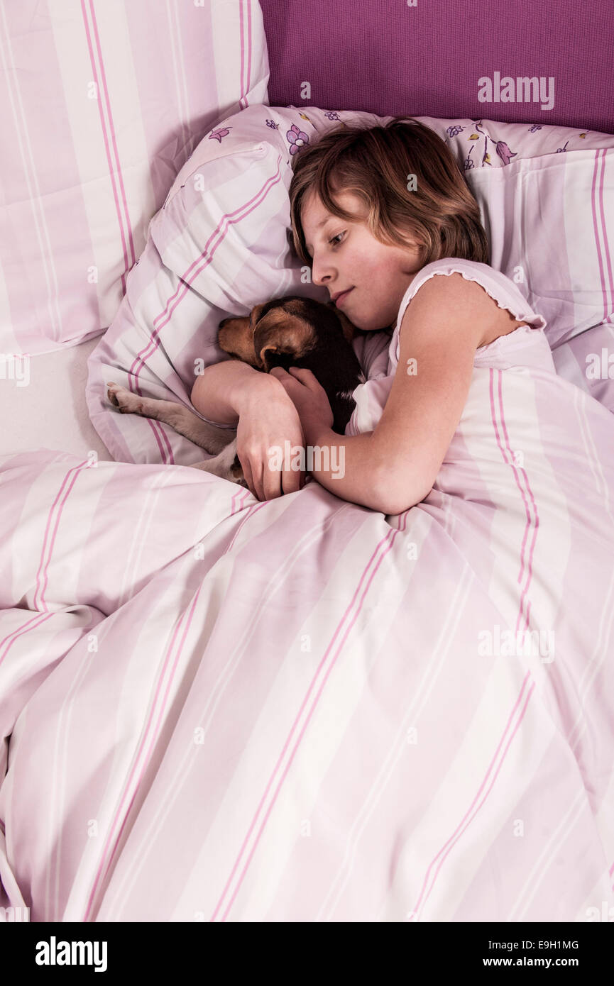Girl lying in bed with a Danish Swedish Farmdog Stock Photo