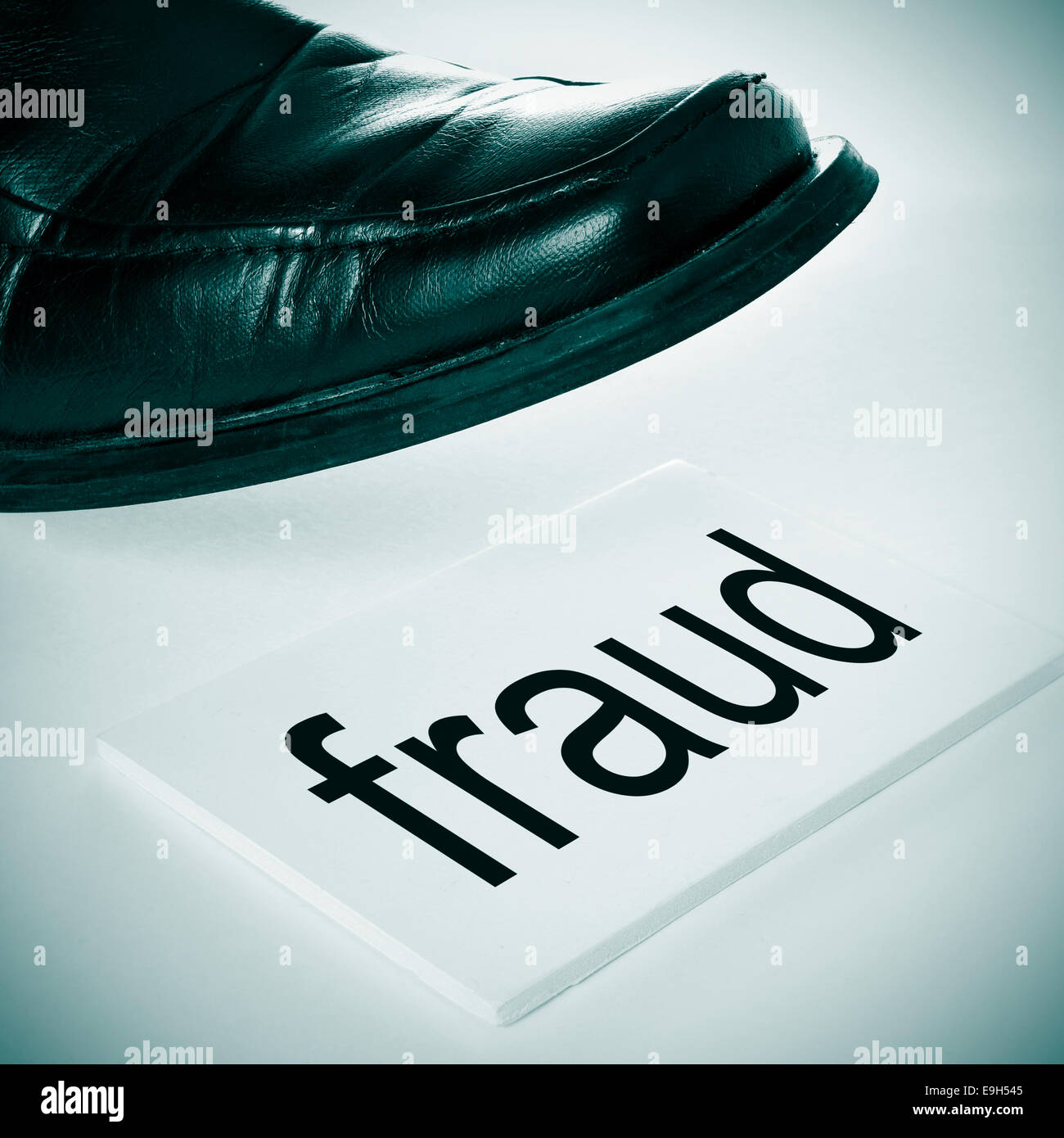a man foot wearing a black shoe stepping in a signboard with the word fraud written in it Stock Photo