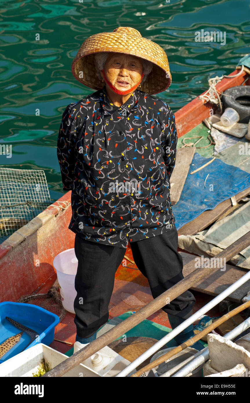 Old Chinese fishmonger with straw hat on her boat, Sai Kung, Hong Kong, China Stock Photo