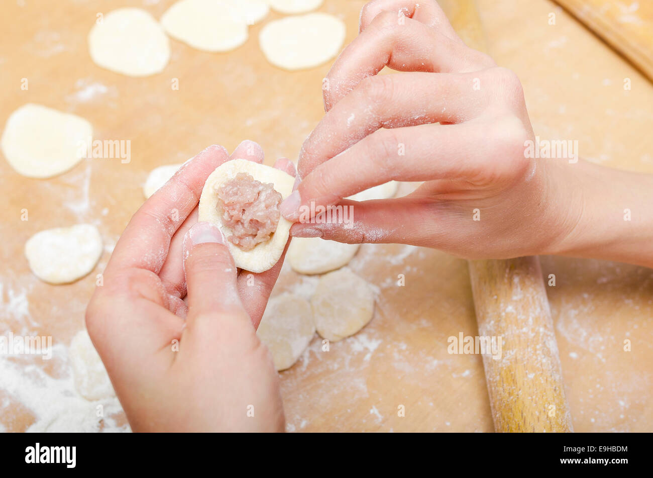Hands of a woman who molds dumplings on kitchen table Stock Photo
