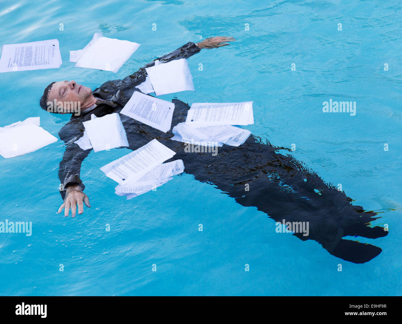 Senior man floating among papers in water Stock Photo