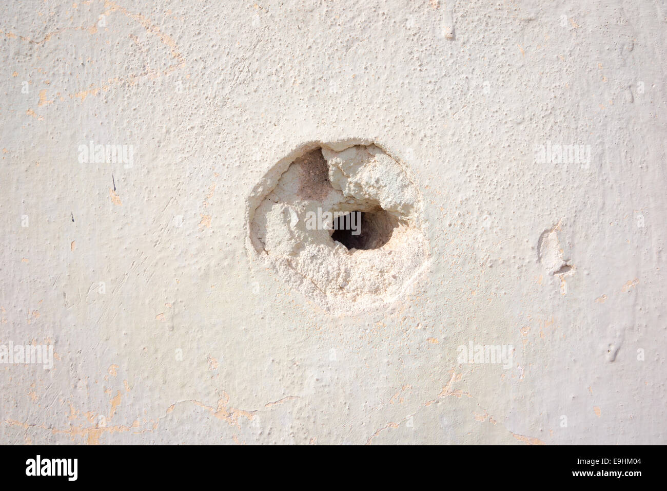Close-up of a bullet hole in an Israeli wall, showing crumbling edges and impact damage to the surface Stock Photo
