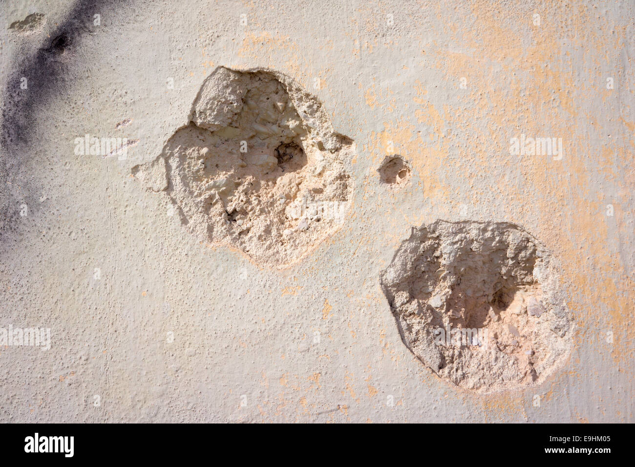 Close-up of a bullet hole in an Israeli wall, showing crumbling edges and impact damage to the surface Stock Photo