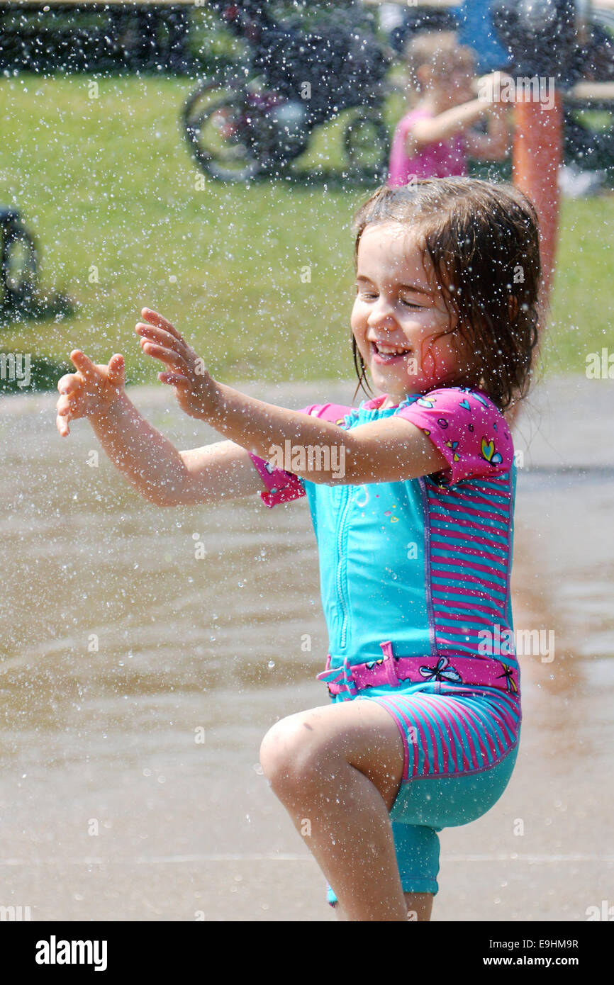 Little girl playing at the water park, focus on the droplets Stock Photo