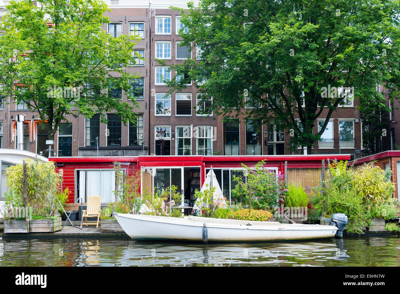 Houseboat at the bank of a canal with a patio and plants, Amsterdam, Netherlands Stock Photo