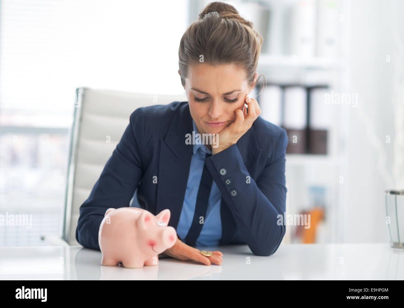 Portrait of sad business woman with piggy bank looking on coin Stock ...