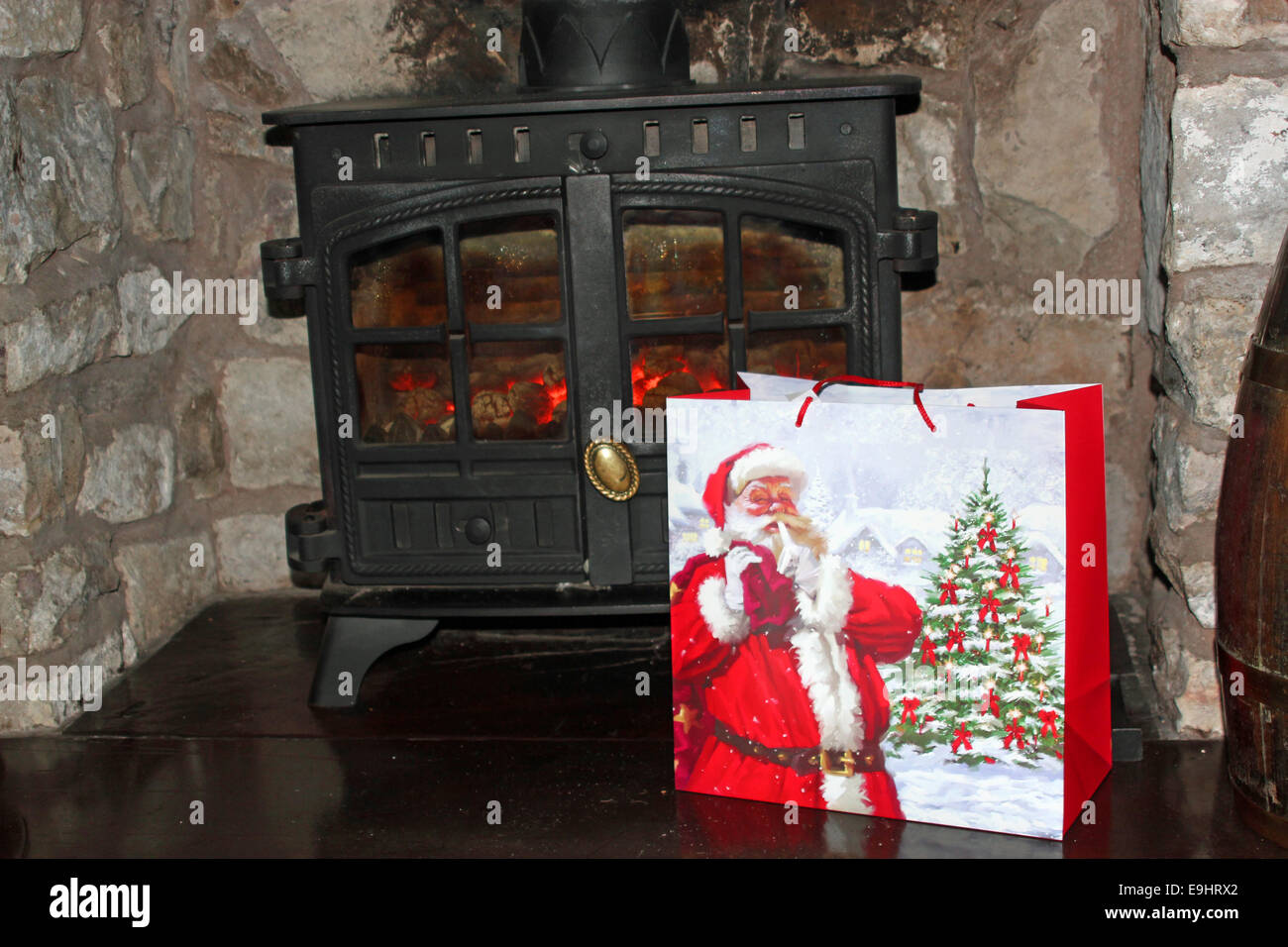Christmas present in a Santa bag front of a log burner Stock Photo