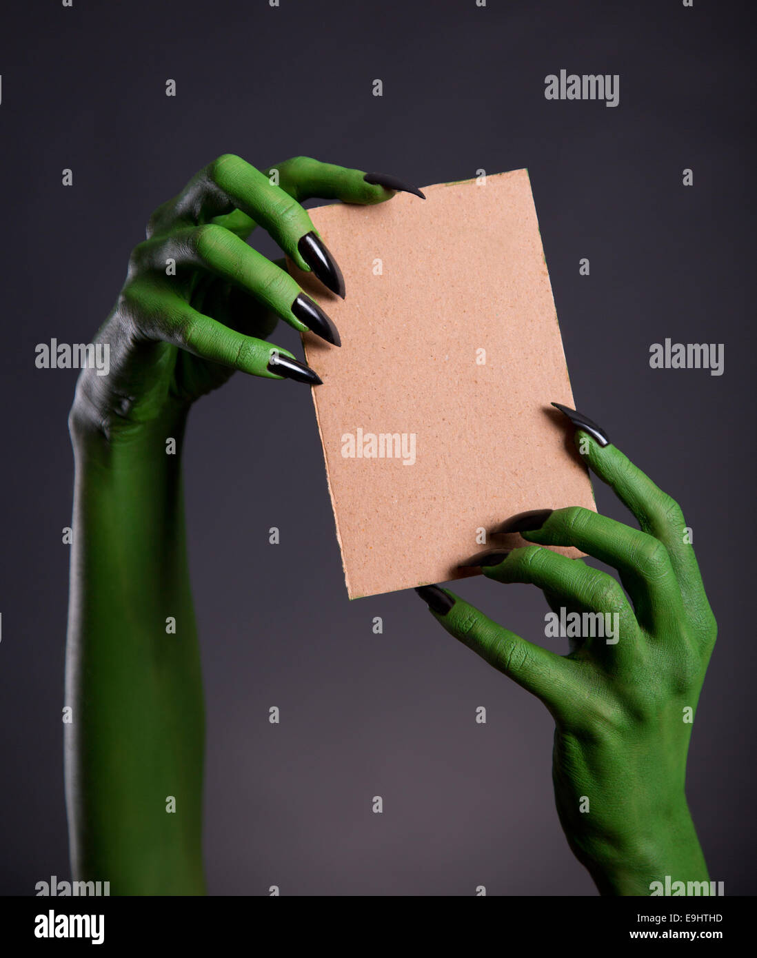 Green monster hands holding empty piece of cardboard, Halloween theme