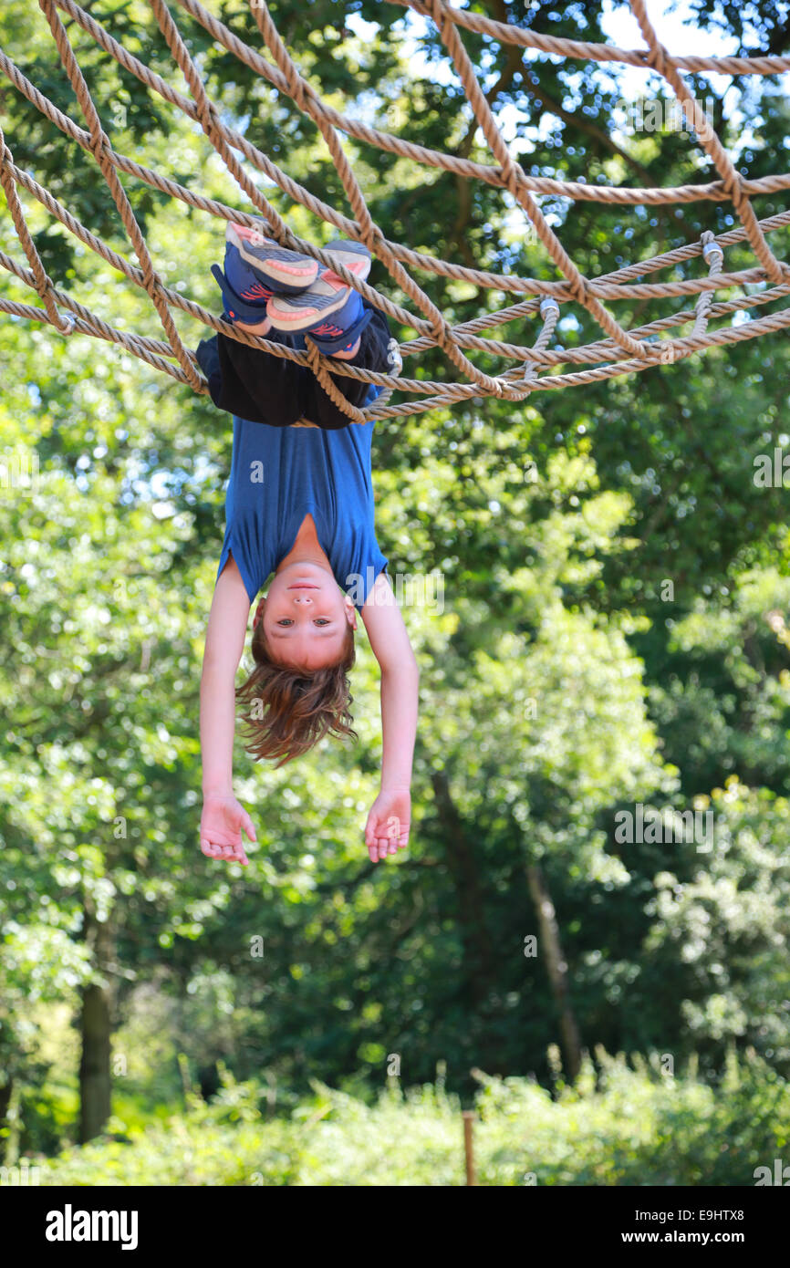 Boy swinging upside down in park Stock Photo