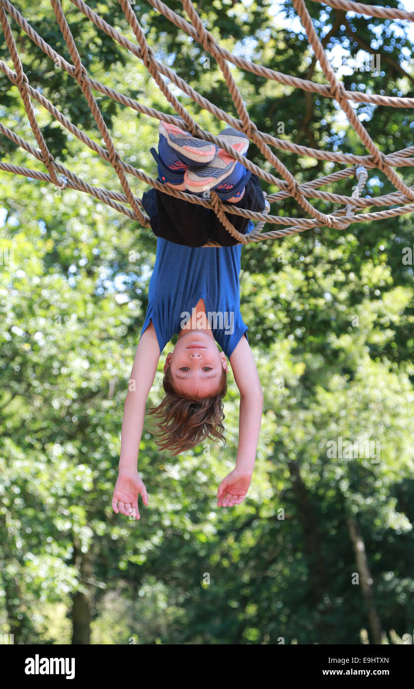Boy swinging upside down in park Stock Photo