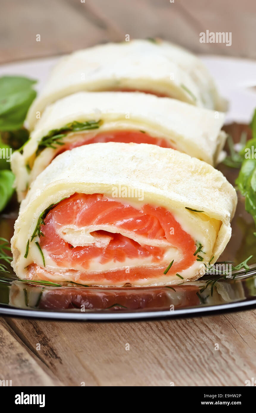 Salmon lavash rolls with cheese and herbs on glass plate, close up view Stock Photo