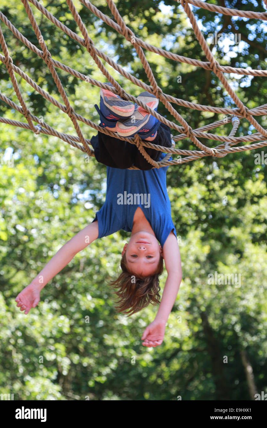 Boy swinging upside down in park Stock Photo Alamy