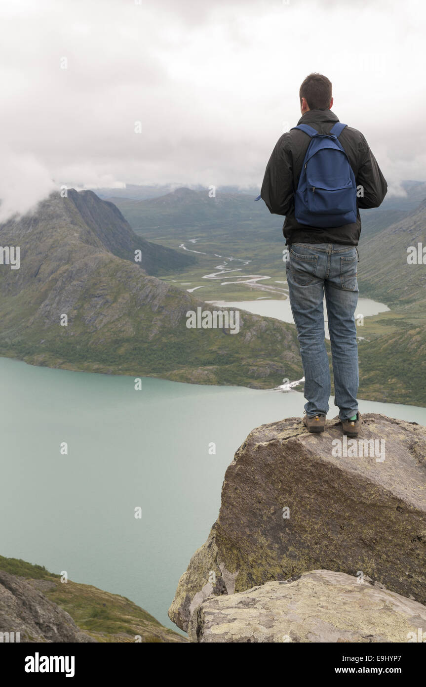 Young man standing on the edge of Besseggen mountain ridge overlooking ...
