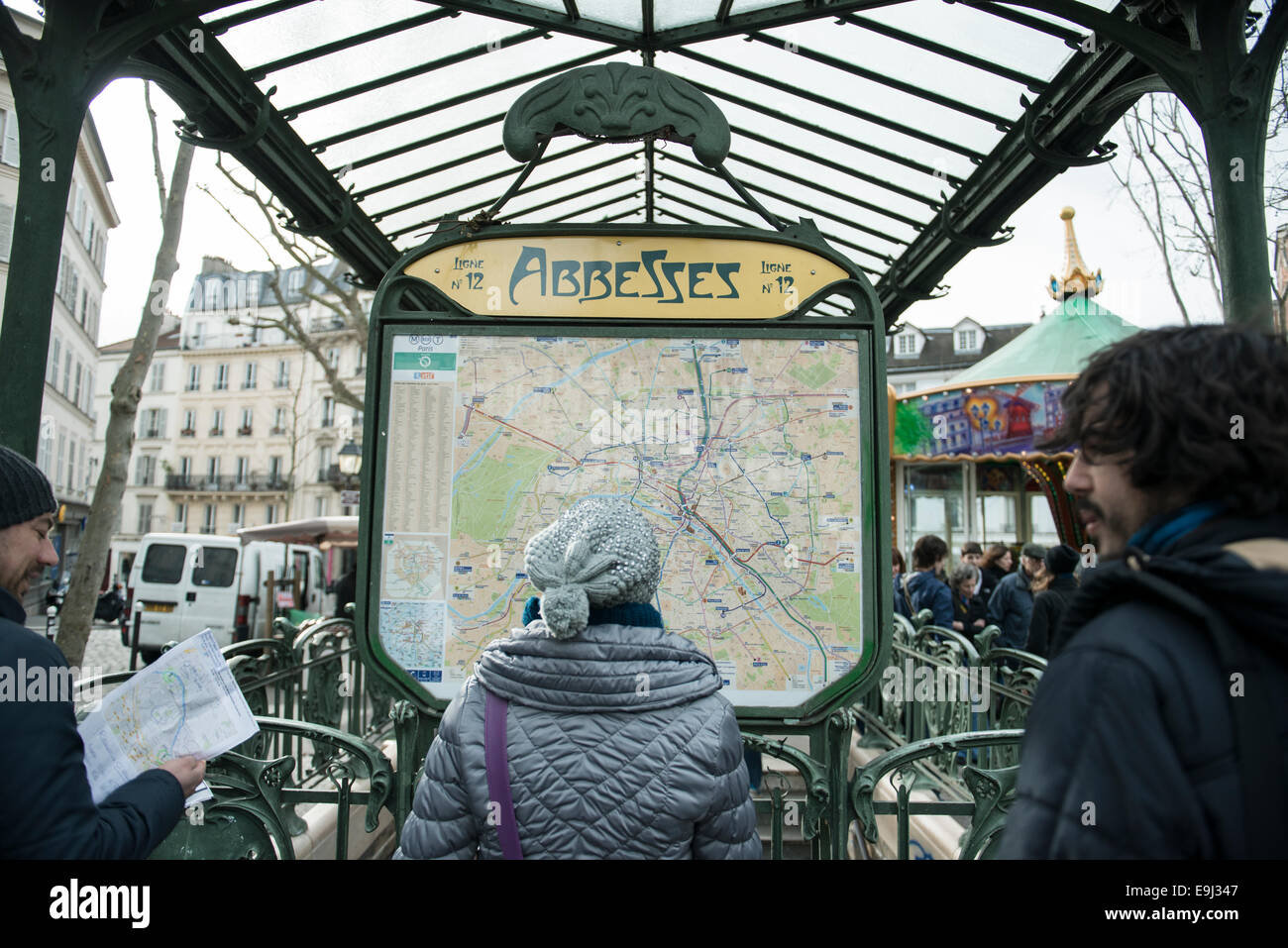a woman in a hat reads the train map outside a paris metro station Stock Photo