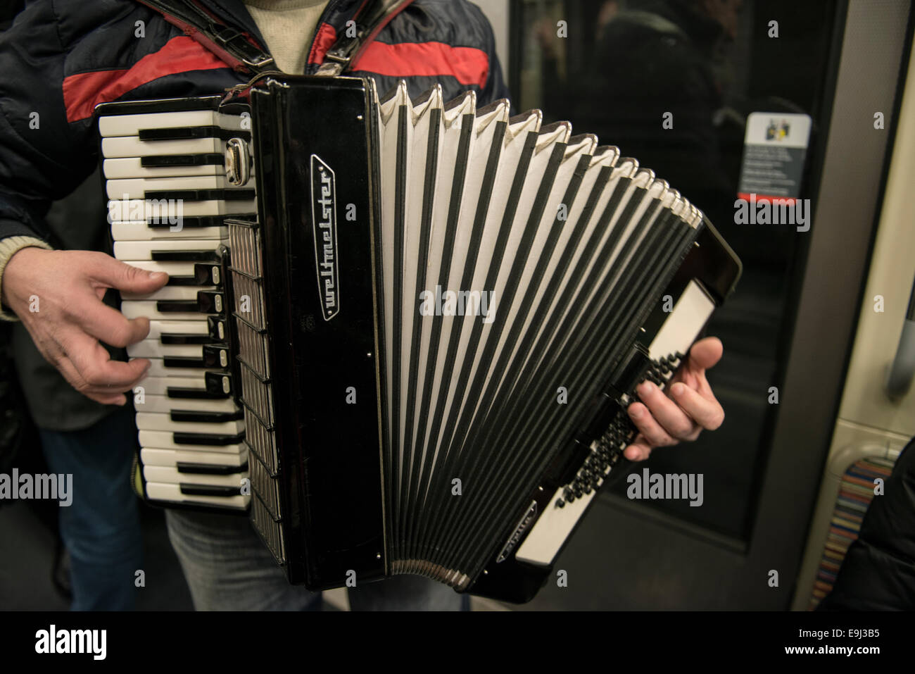 an accordion player busks on the paris metro trains with a traditional wind instrument Stock Photo