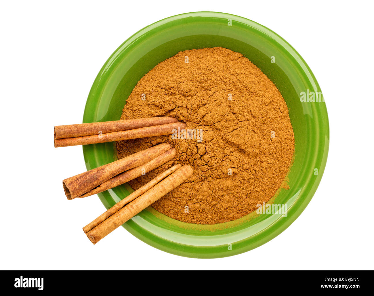 cinnamon  (cassia)  bark powder and sticks on an isolated green ceramic bowl Stock Photo