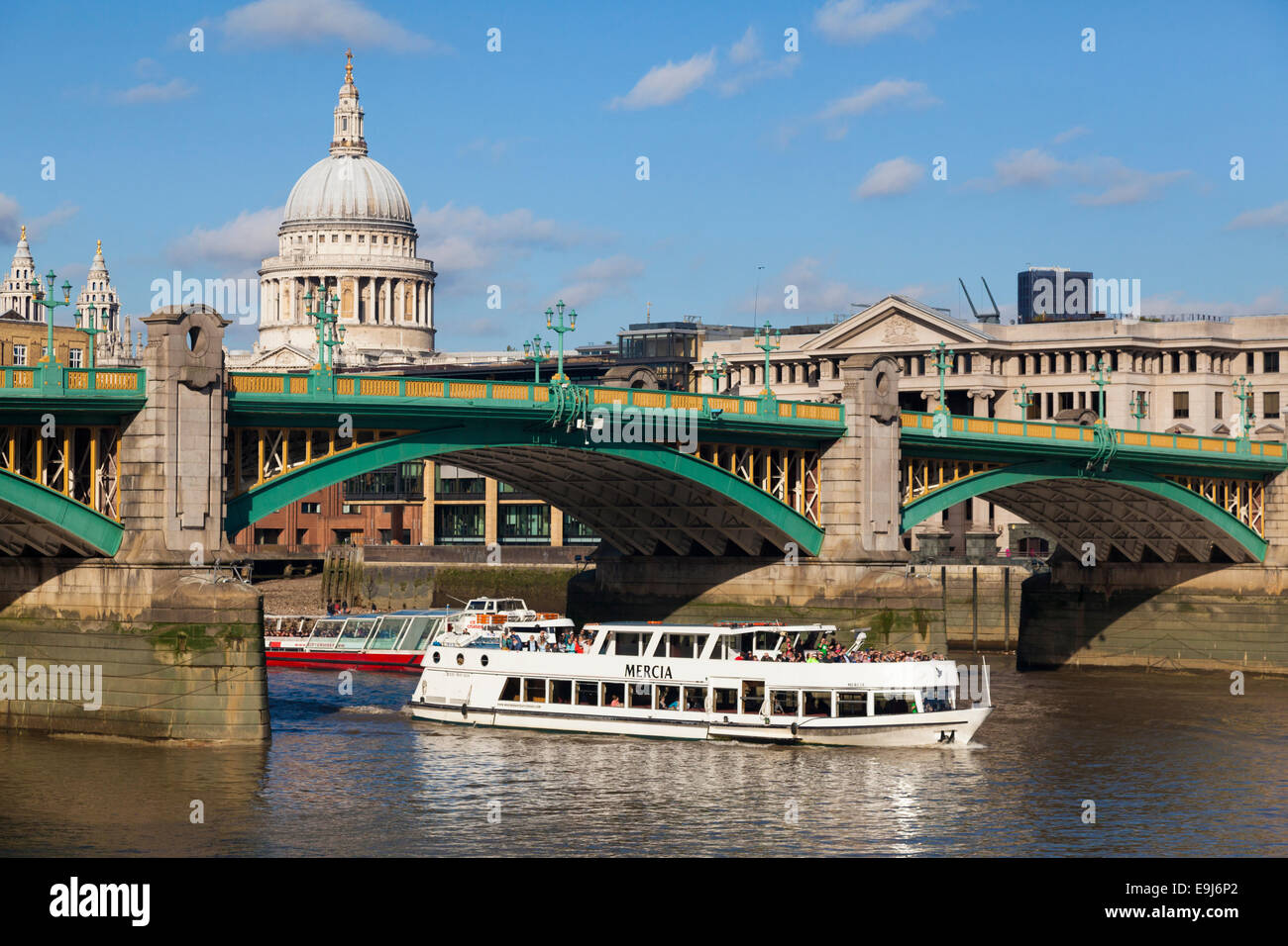 River busses pass under Southwark Bridge on the River Thames with St Paul's Cathedral in background, London, UK Stock Photo