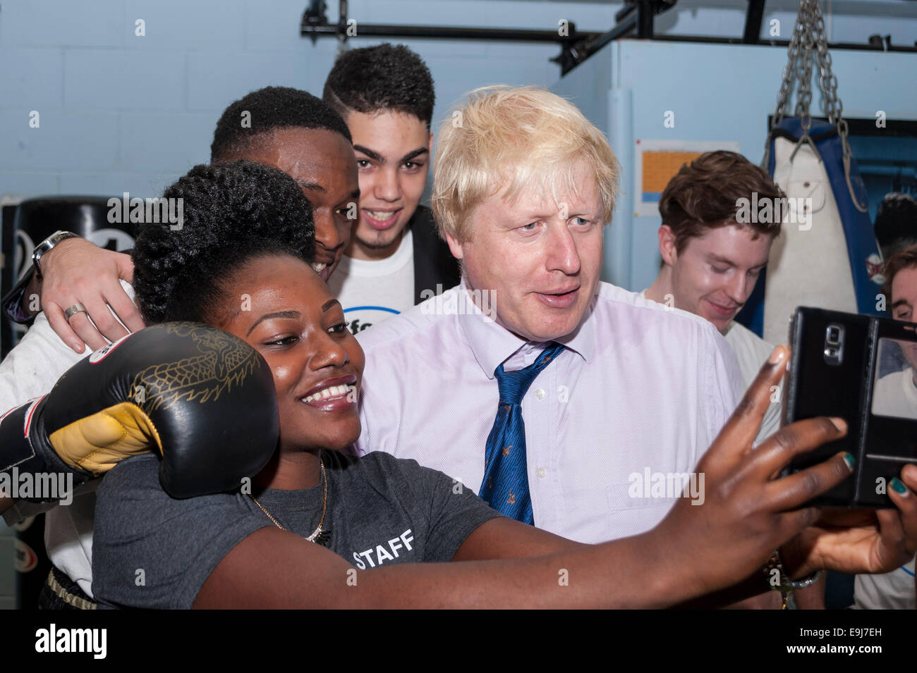 London, UK. 28th October, 2014. The Mayor of London, Boris Johnson visited a training session at Fight for Peace Academy in North Woolwich, Newham where he met some of the young people being helped by the charity. Fight for Peace uses boxing and martial arts combined with education and personal development to realise the potential of young people in the borough at risk of crime and violence.  First established in Rio in 2000 by Luke Dowdney MBE, it was replicated in Newham in 2007and is now expanding globally.  Pictured : the Mayor poses for selfies.   Credit:  Stephen Chung/Alamy Live News Stock Photo