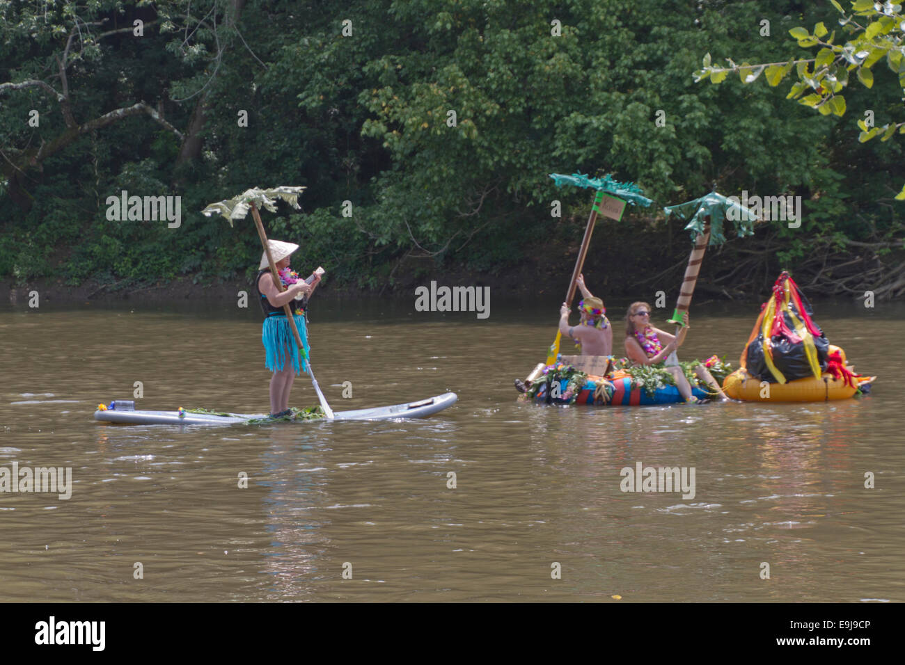 Costumed people float down the French Broad River on a creative palm island surfboard in the