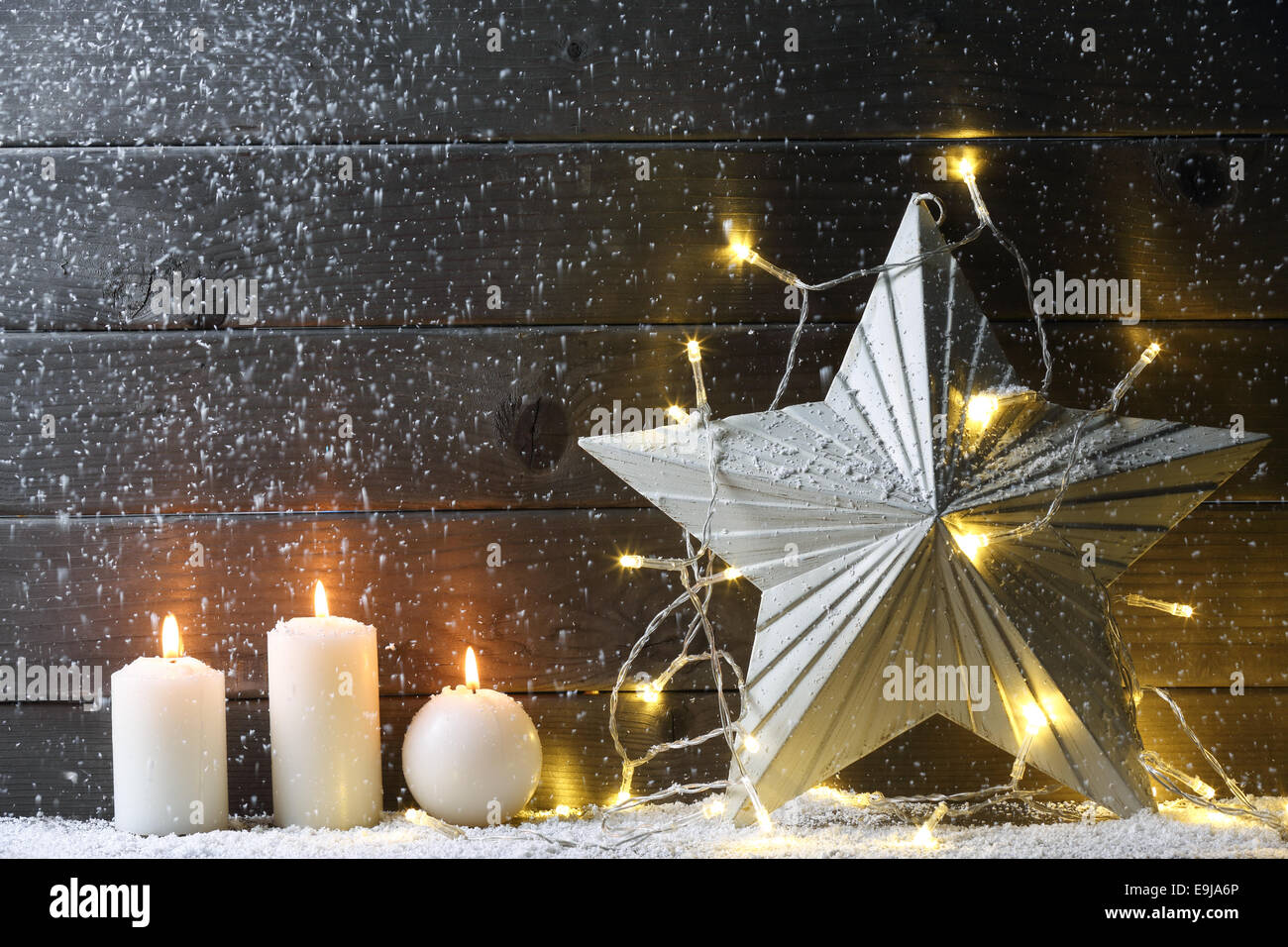Burning candles,metal star and Christmas lights on wood background. Stock Photo