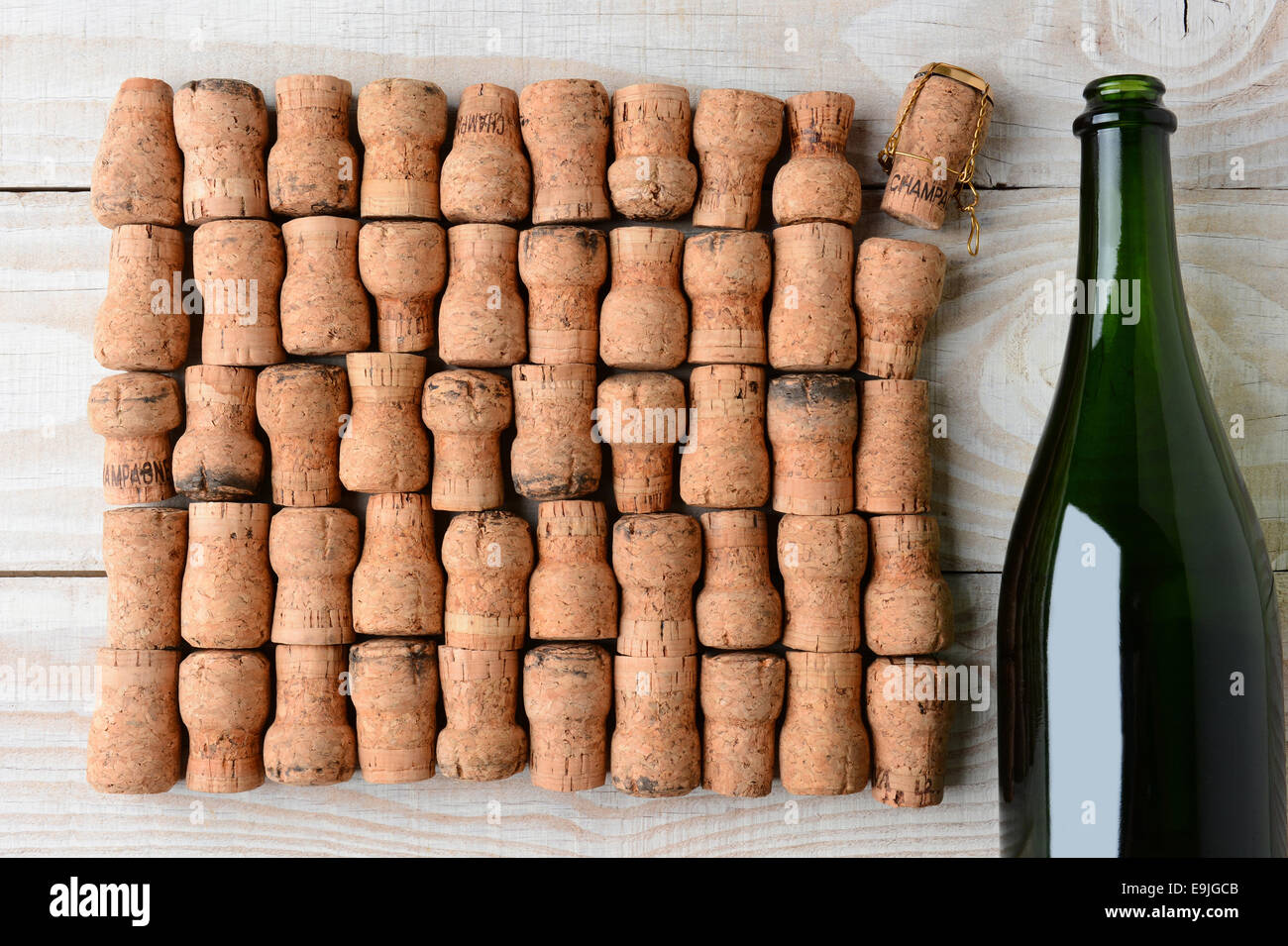 Overhead shot of a empty champagne bottle without label and corks. Closeup on a rustic white wood table. Horizontal format with Stock Photo