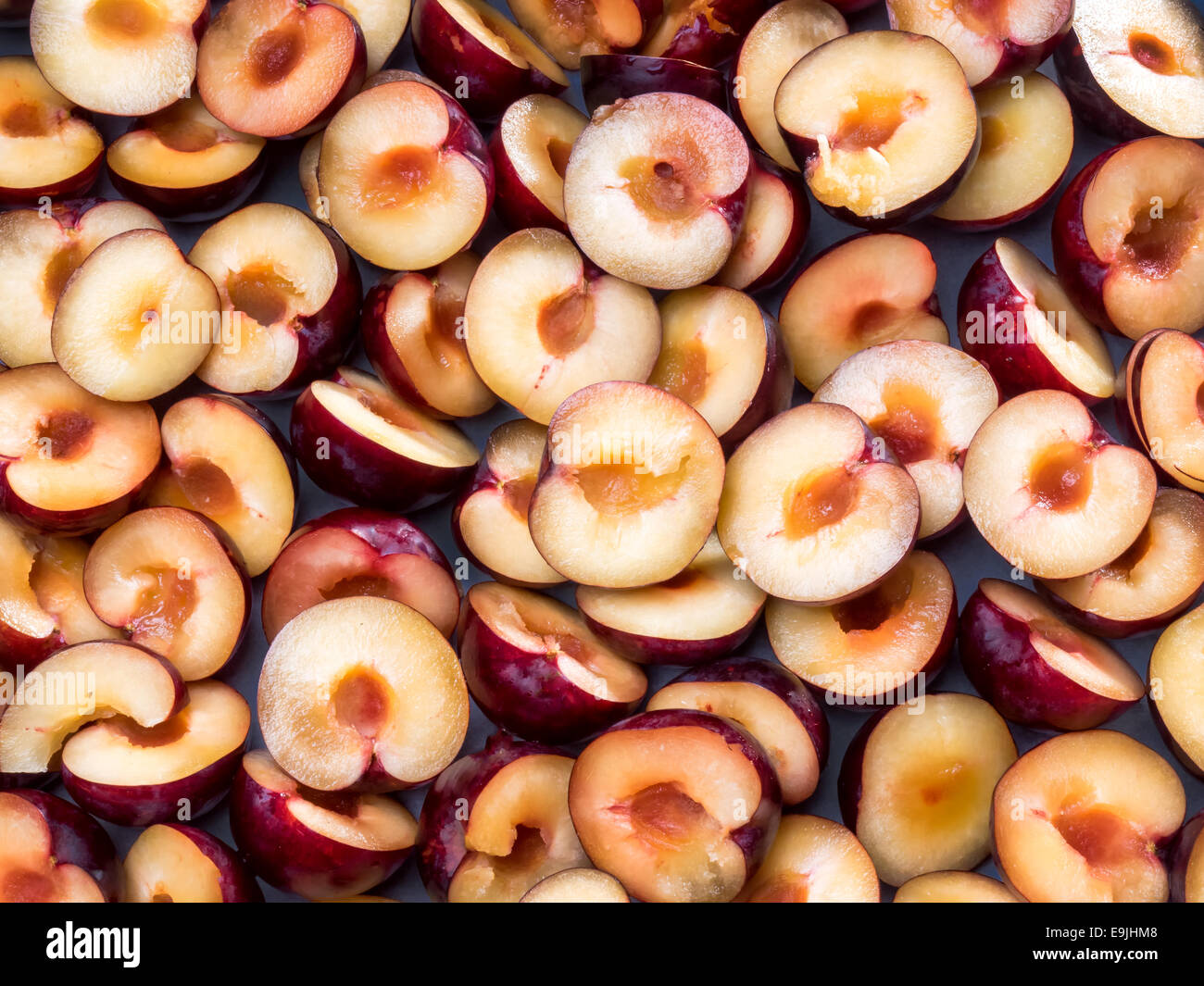 Purple plums cut in halves with stones Stock Photo Alamy