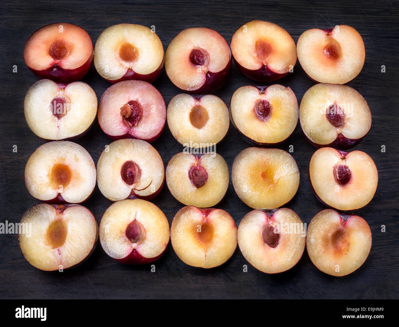 Twenty purple plums cut in halves with stones Stock Photo