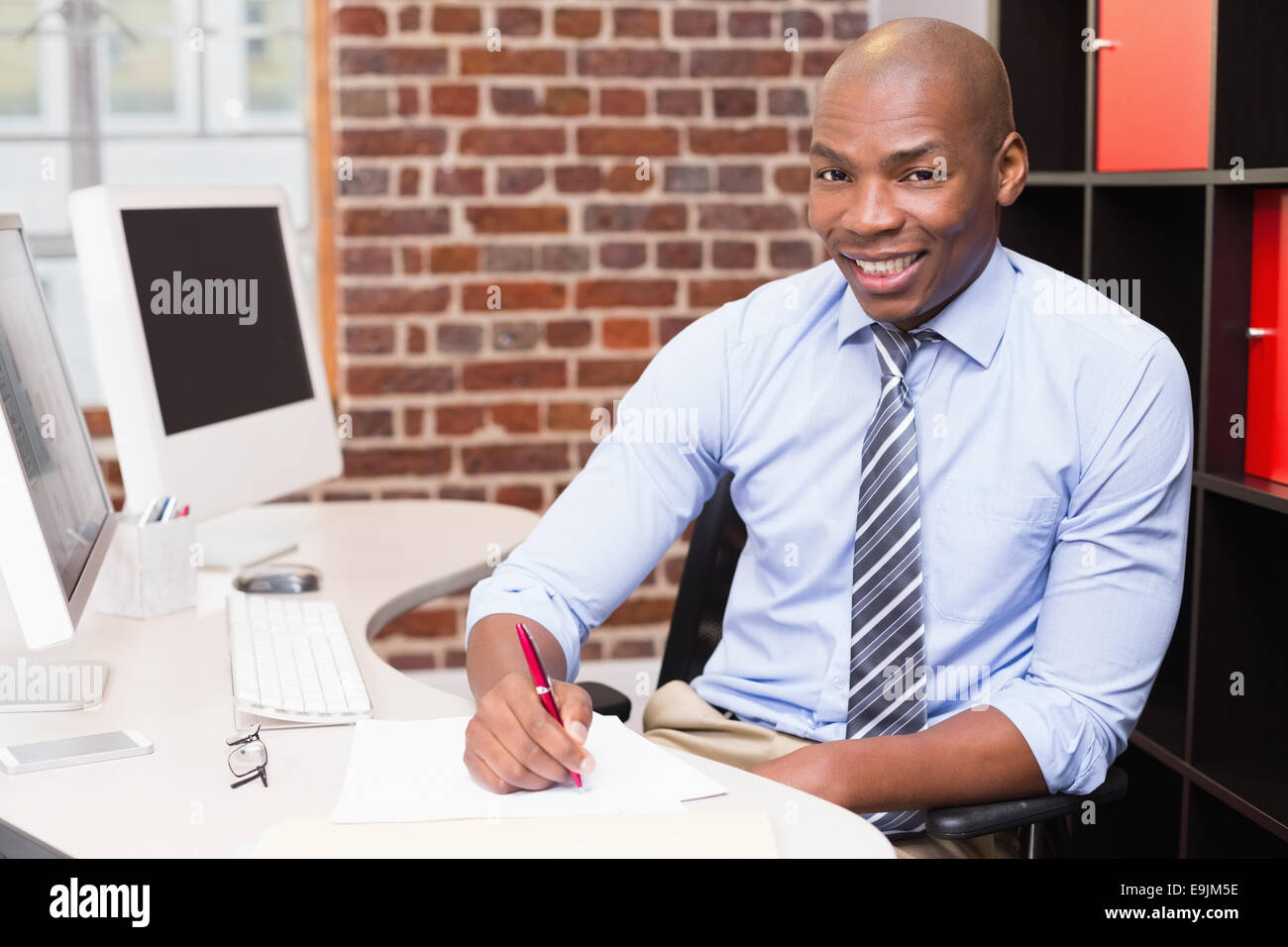 Portrait of businessman writing document at desk Stock Photo - Alamy