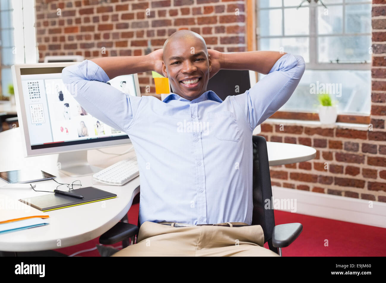 Businessman sitting with hands behind head in office Stock Photo