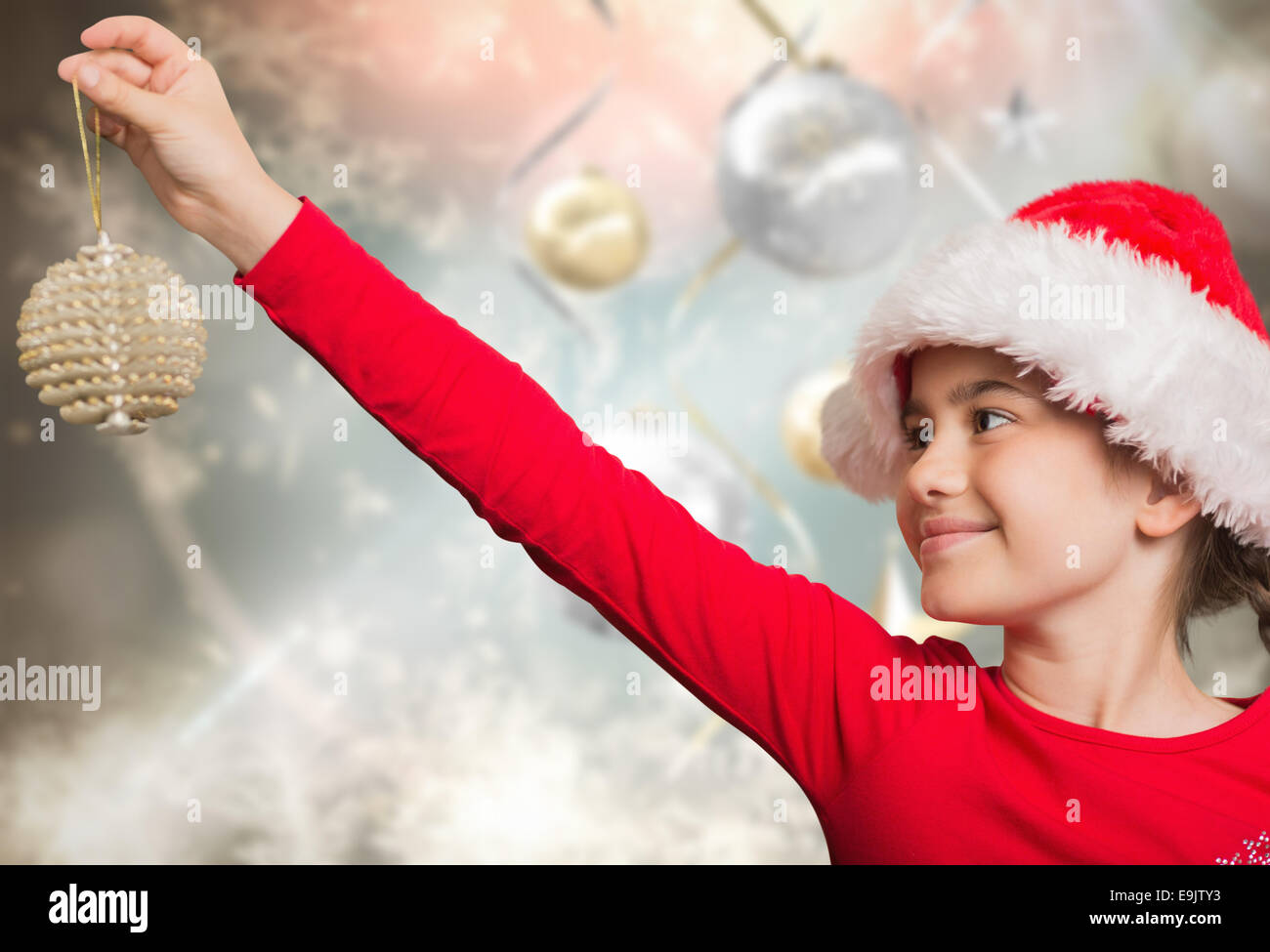 Composite image of festive girl hanging decoration Stock Photo