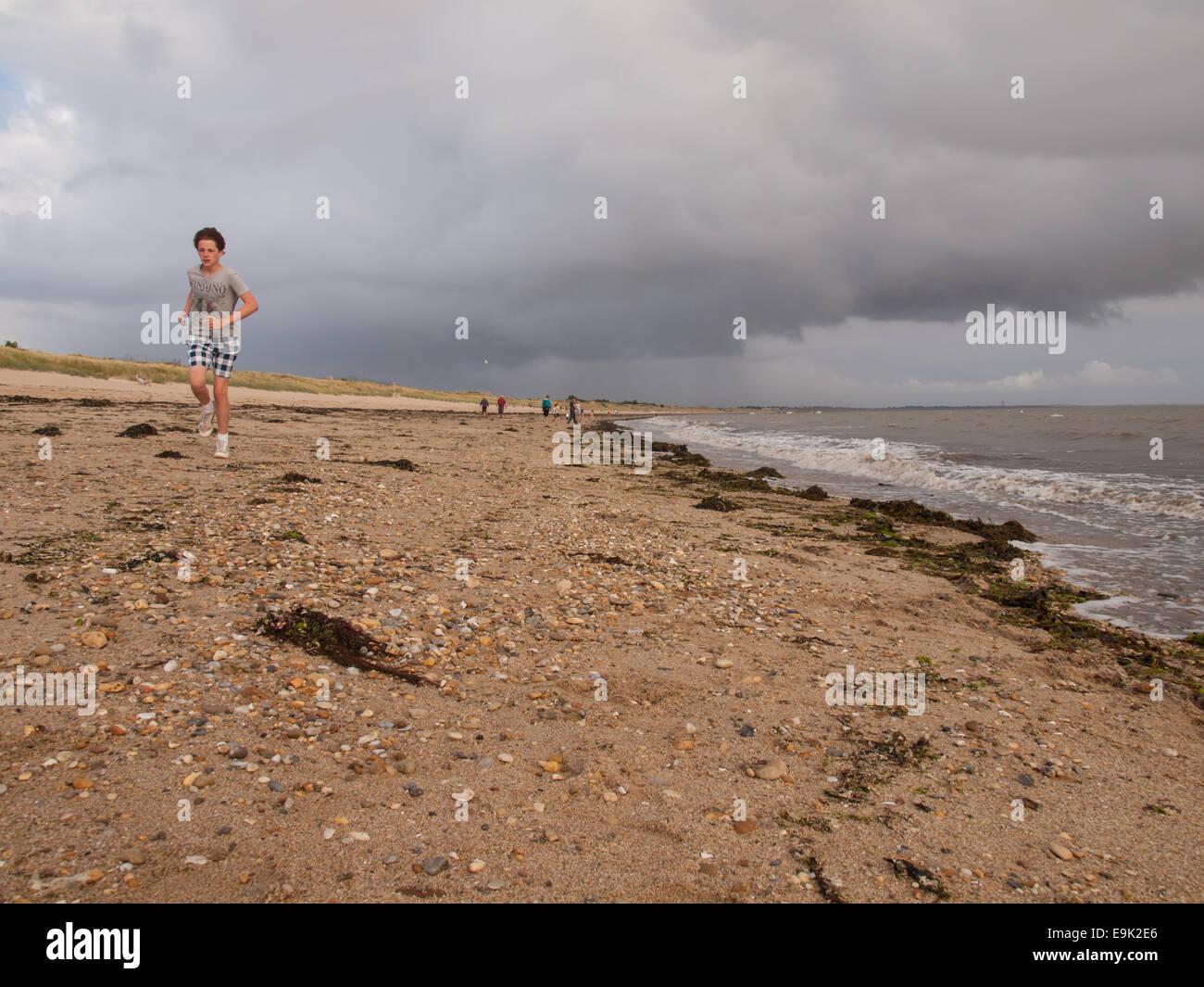 runner on the  the beach under stormy skies in evening light. noimoutier, vendee, france. Stock Photo