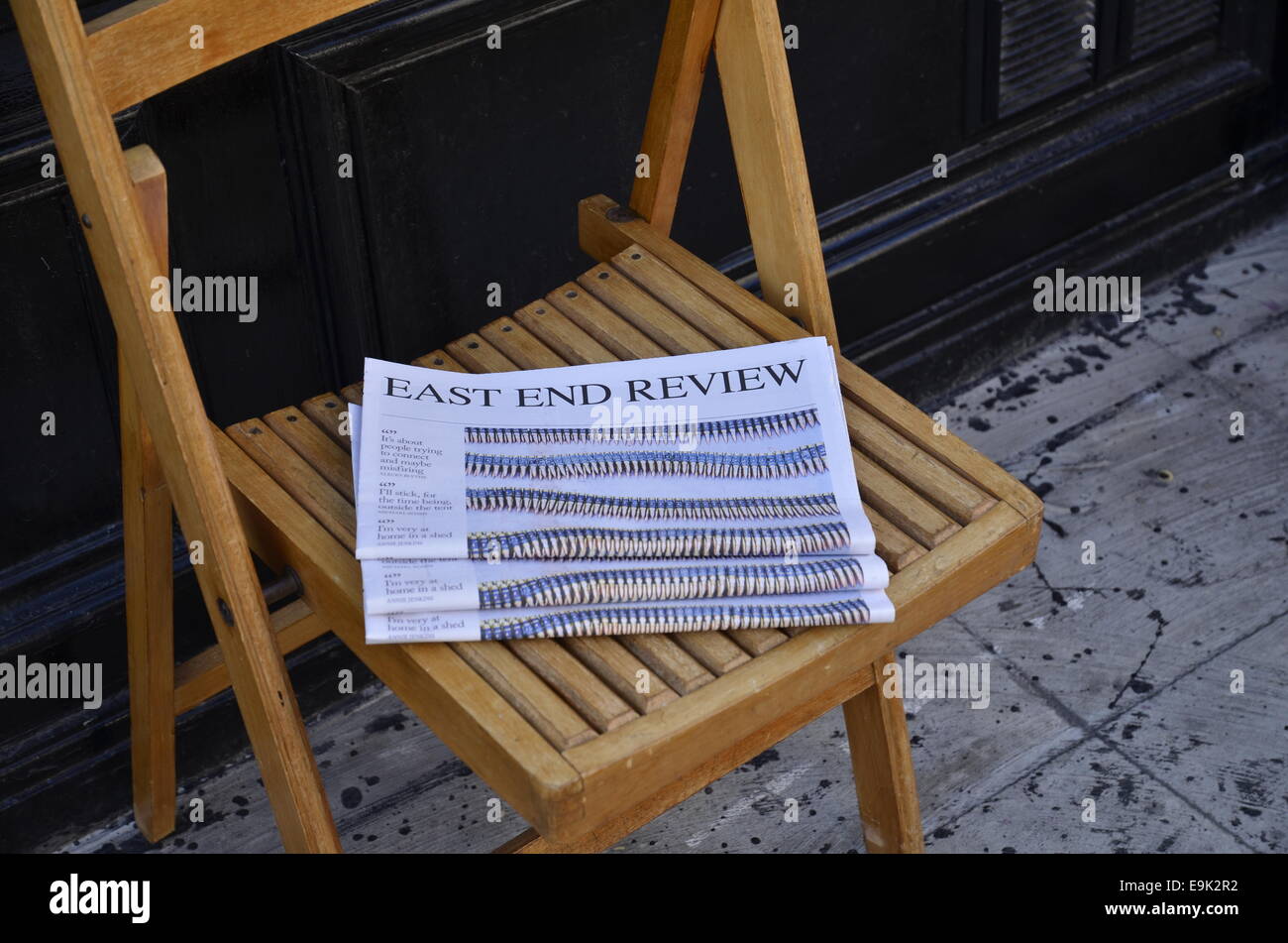 Copies of the local newspaper East End Review outside a restaurant in Spitalfields, east London Stock Photo