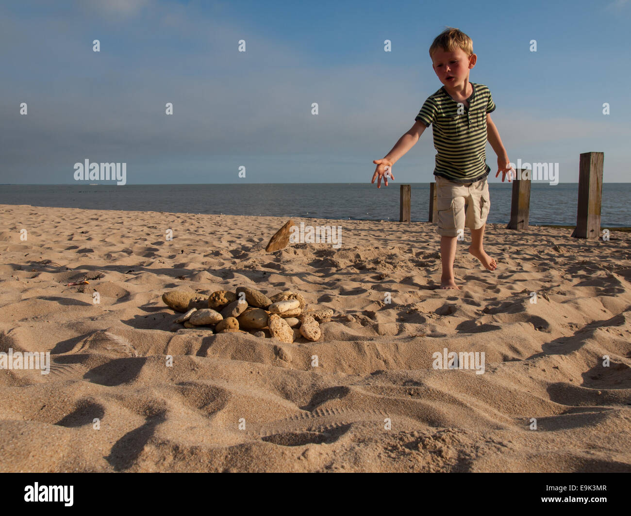 small boy collecting stones on a sandy beach Stock Photo