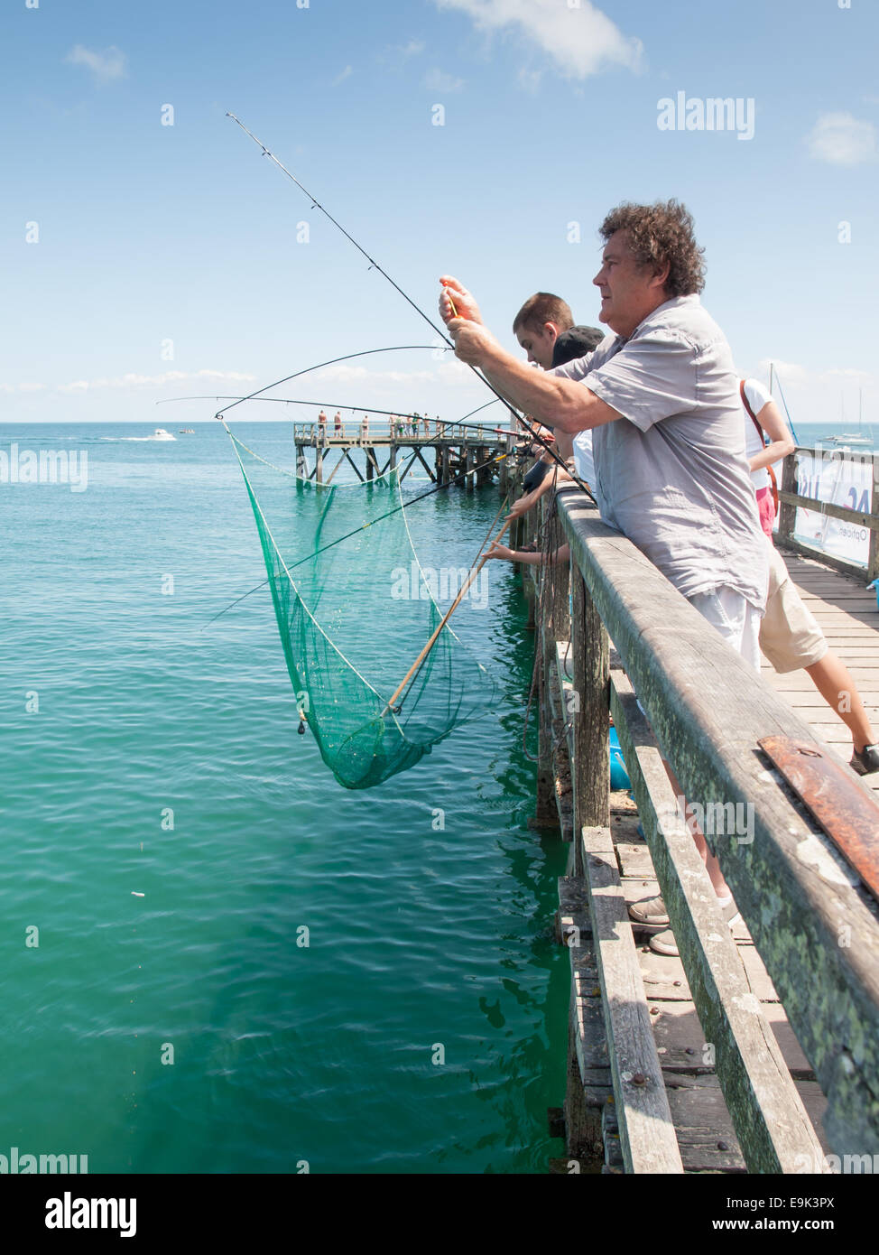 men fishing with rods and a carrelet lift net from a pier Noirmoutier-en-l'Île on the island noirmoutier Stock Photo