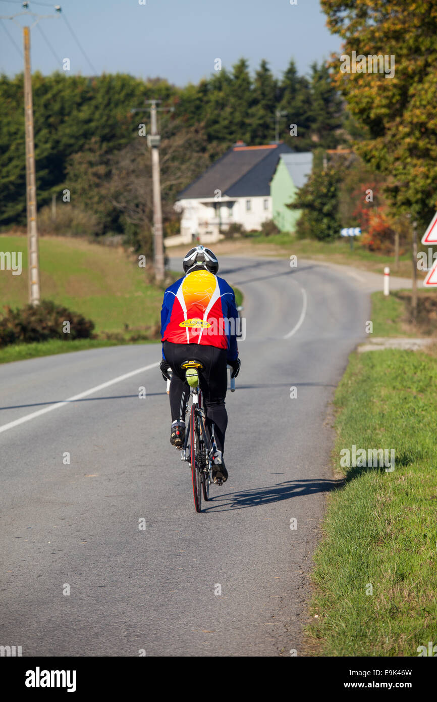 A local club member cycles along the main road from La Chez to Loudeac in Cotes-D'armor Stock Photo