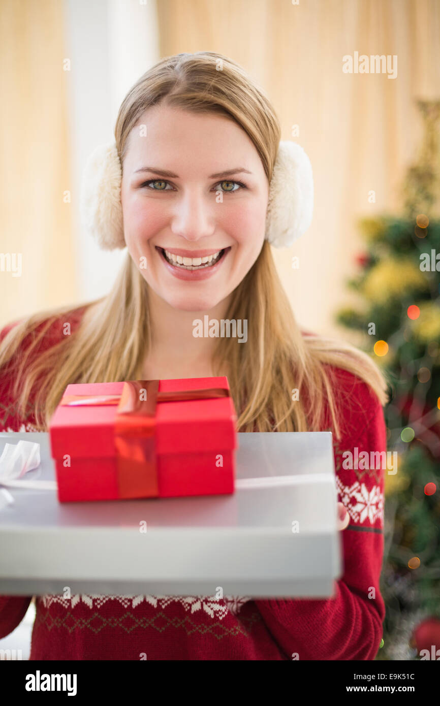 Smiling blonde wearing earmuffs while holding gifts Stock Photo