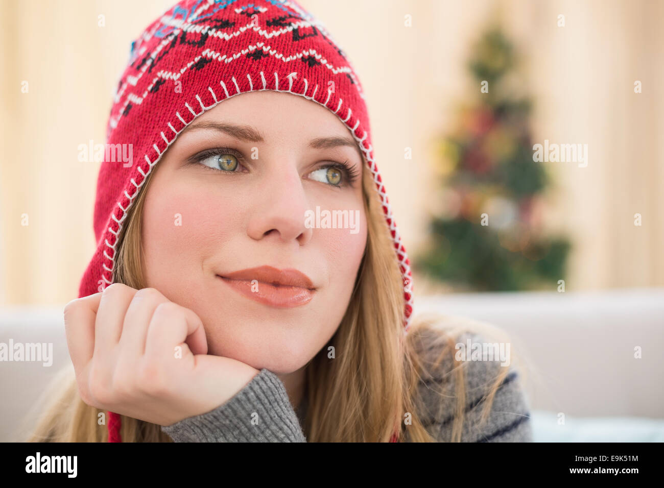 Woman in winter hat thinking with head on hand Stock Photo