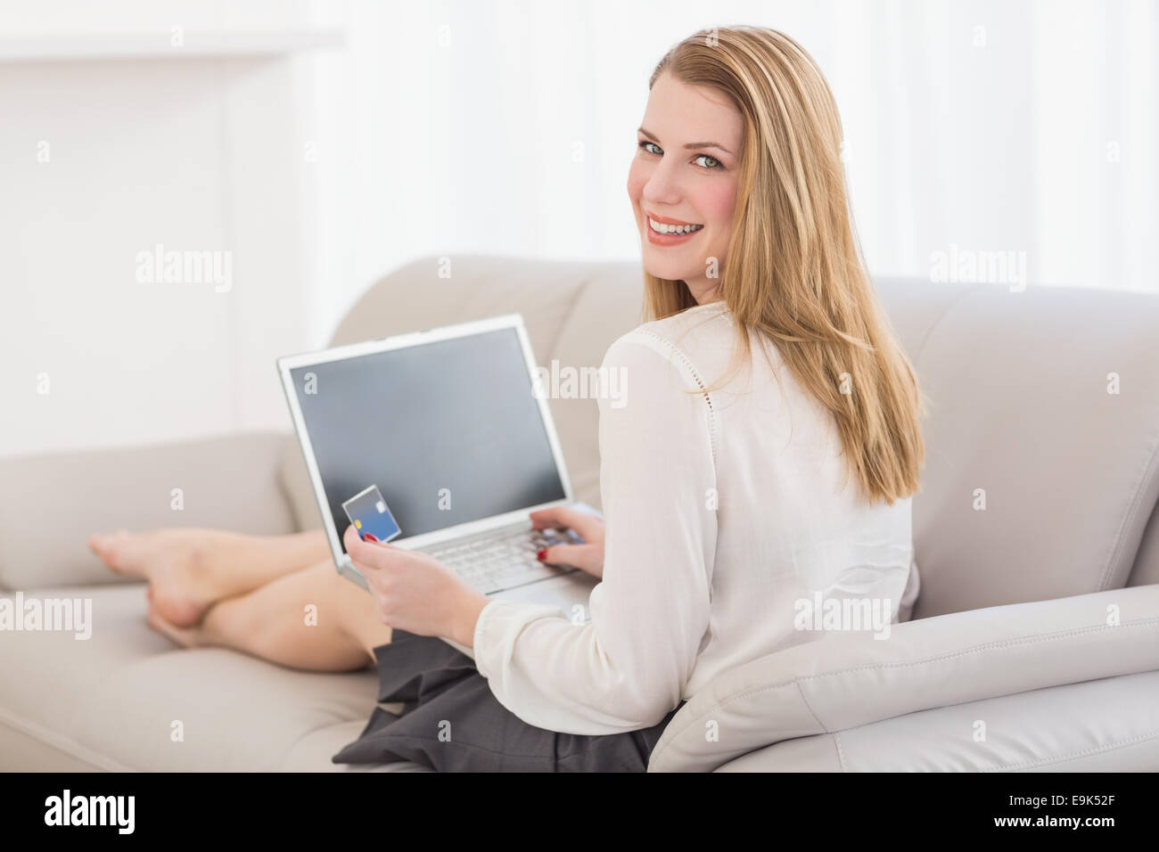 Pretty blonde looking over shoulder while shopping online Stock Photo