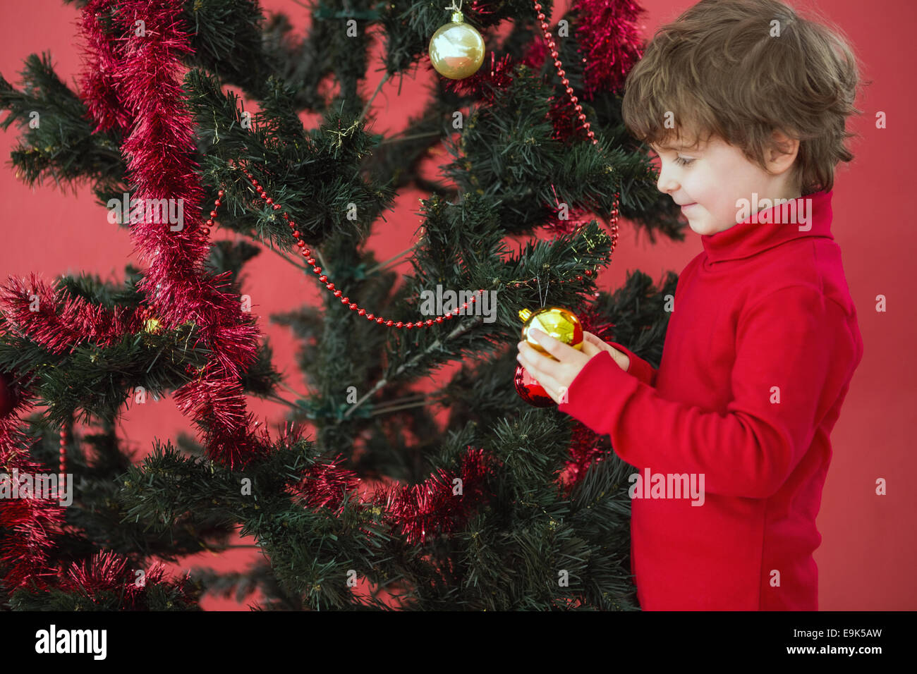 Festive little boy hanging a bauble Stock Photo
