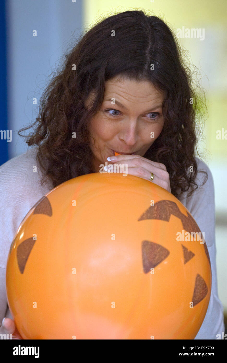 Woman blowing up a balloon for Liphook Carnival, October 25, 2014, Liphook, Hampshire, UK. Stock Photo