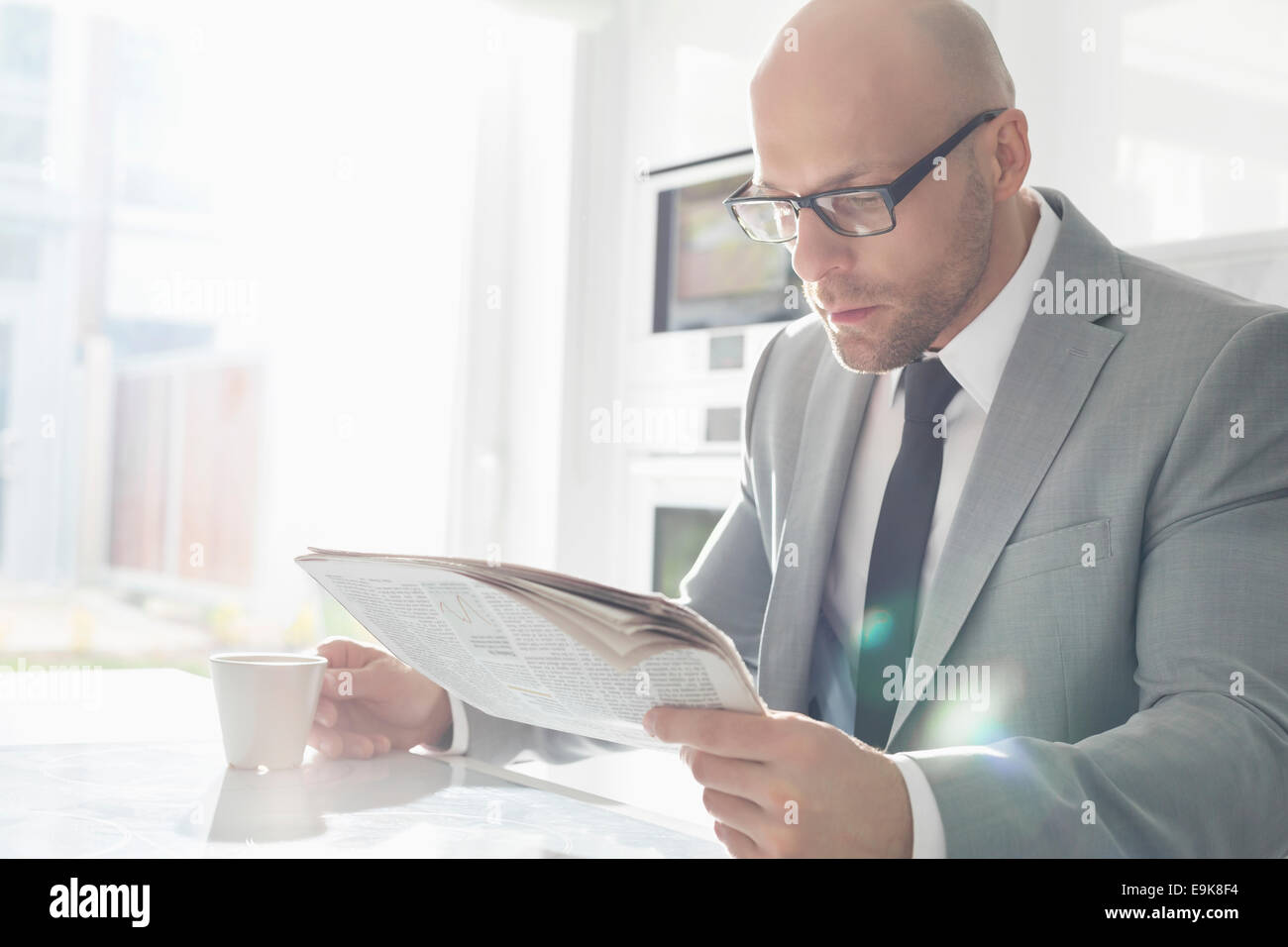 Mid adult businessman having coffee while reading newspaper at home Stock Photo