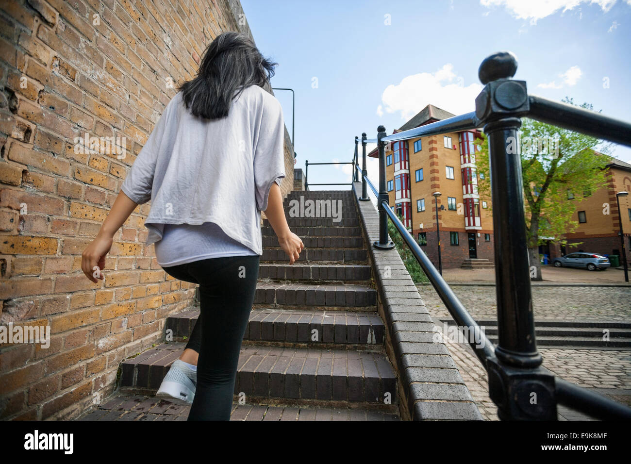 Rear view of young woman walking up stairs outdoors Stock Photo
