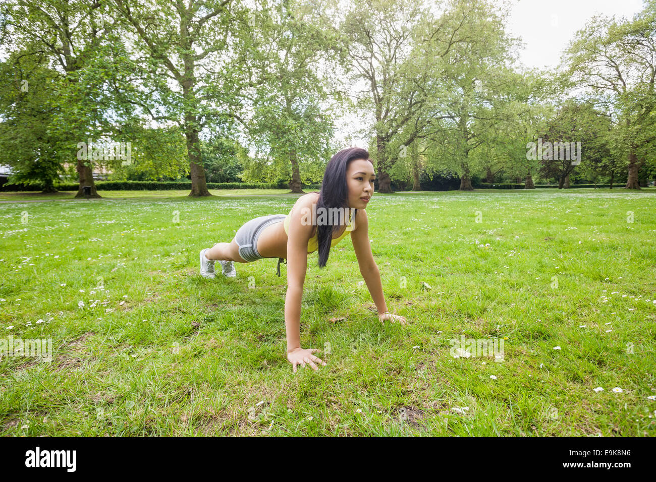 Full length of young fit woman performing pushups at park Stock Photo
