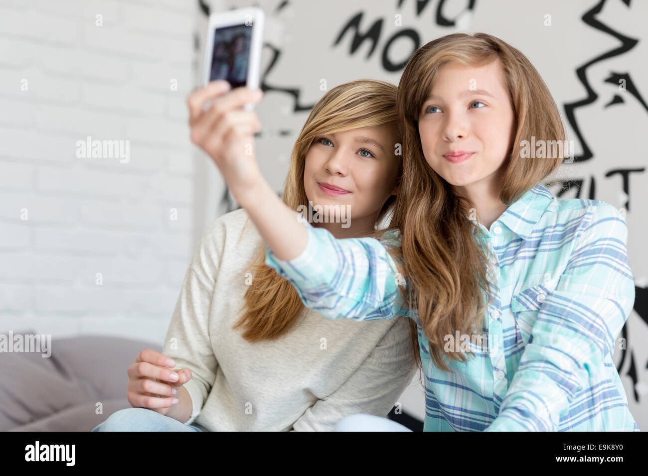 Cute sisters taking photos with smart phone at home Stock Photo