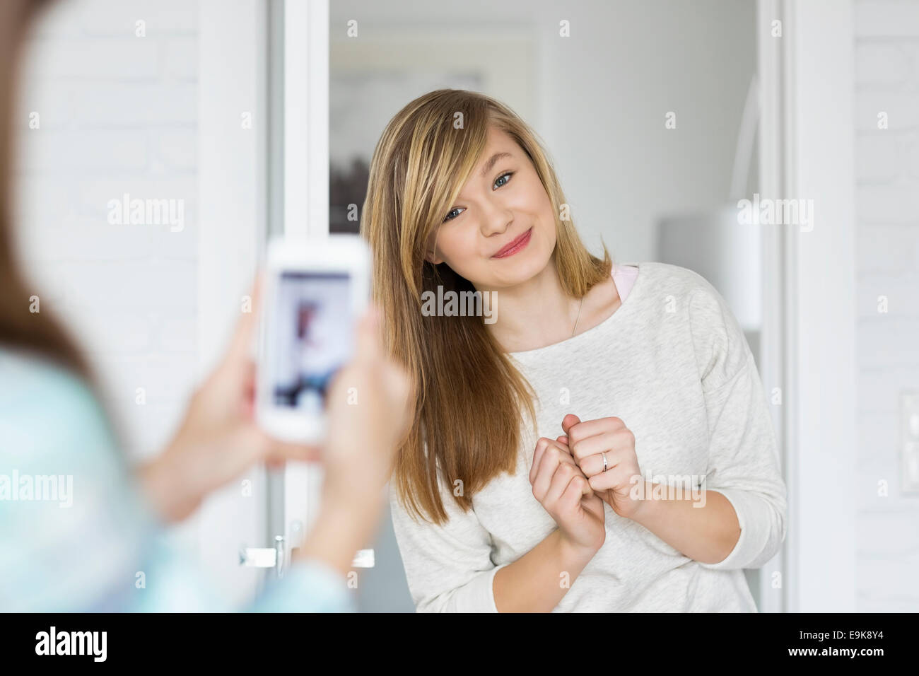 Girl photographing sister through smart phone at home Stock Photo