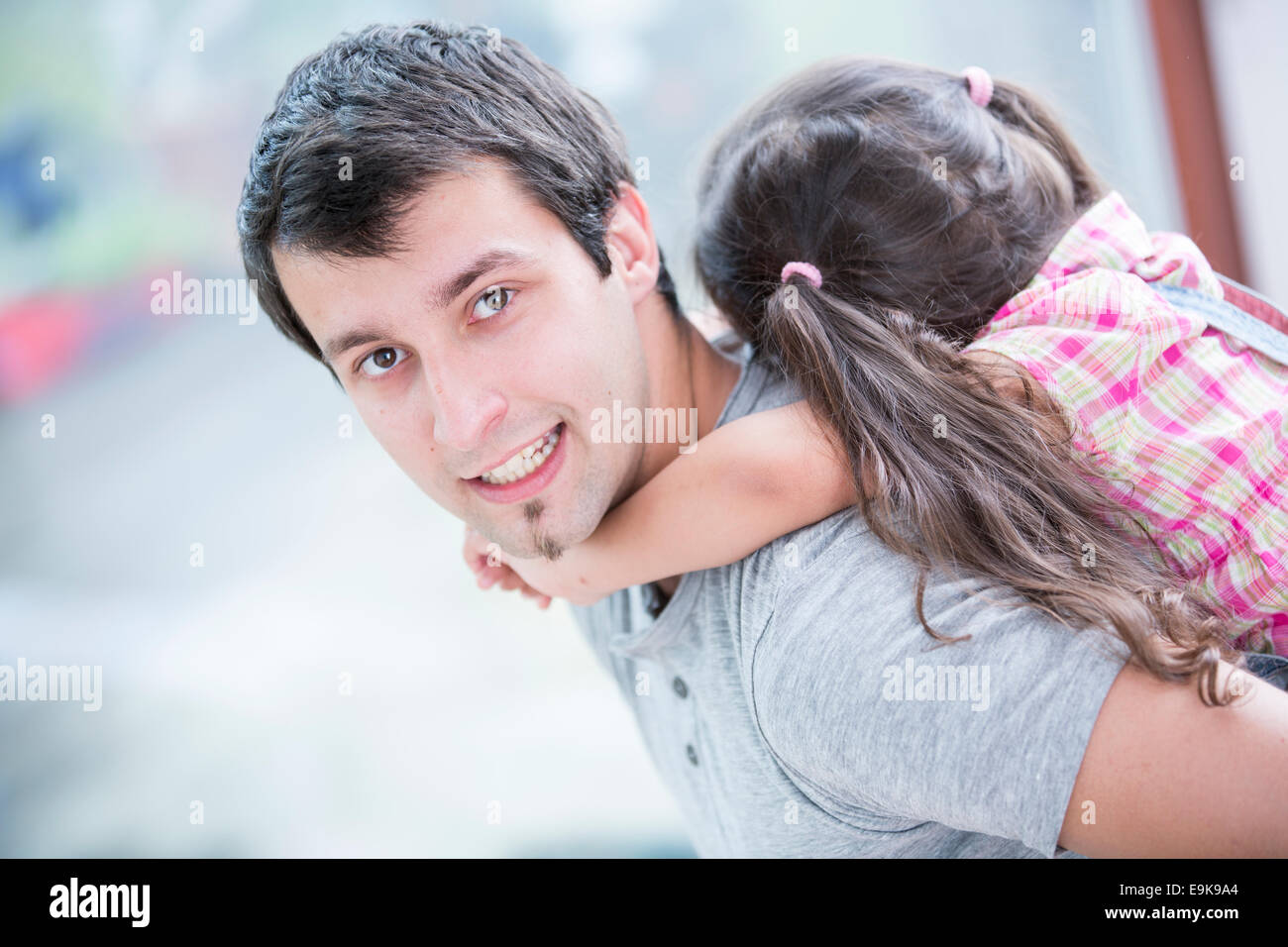 Side view portrait of young man piggybacking little daughter at home Stock Photo